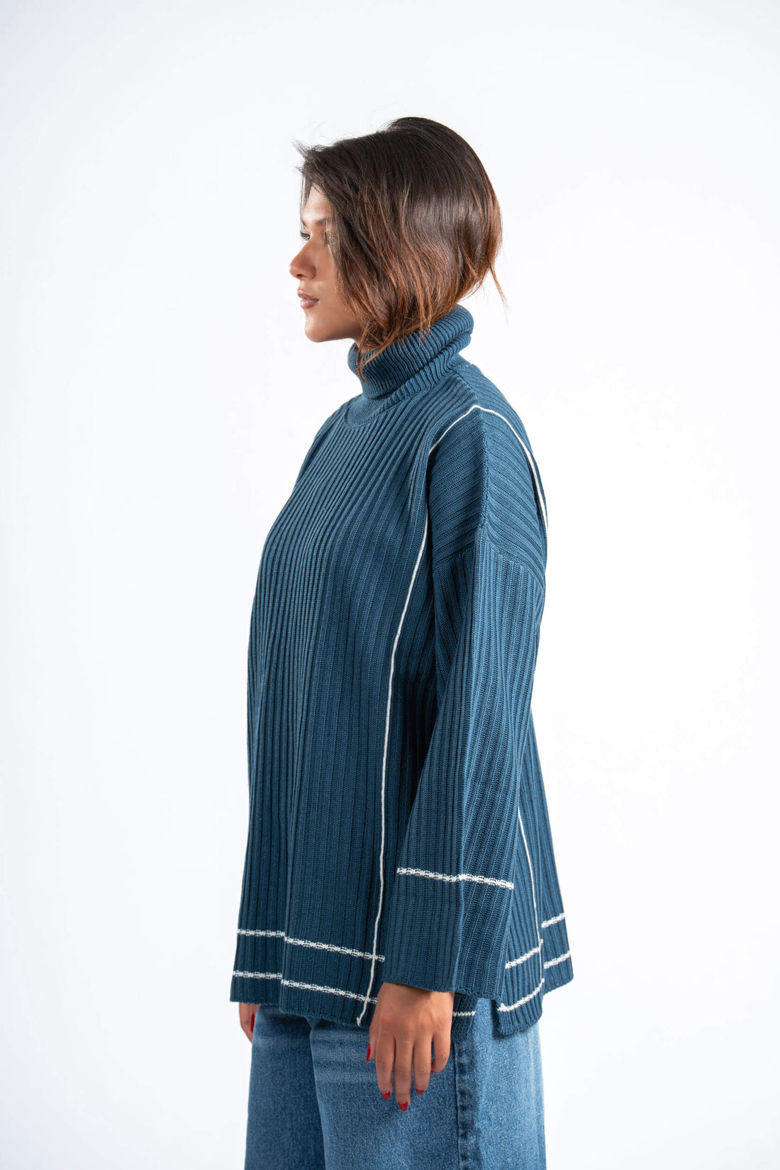 Person wearing a blue ribbed sweater with white trim on a white background