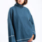 Person wearing a blue ribbed sweater with white trim on a white background