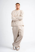 Man wearing a beige sweater and pants set on a white background