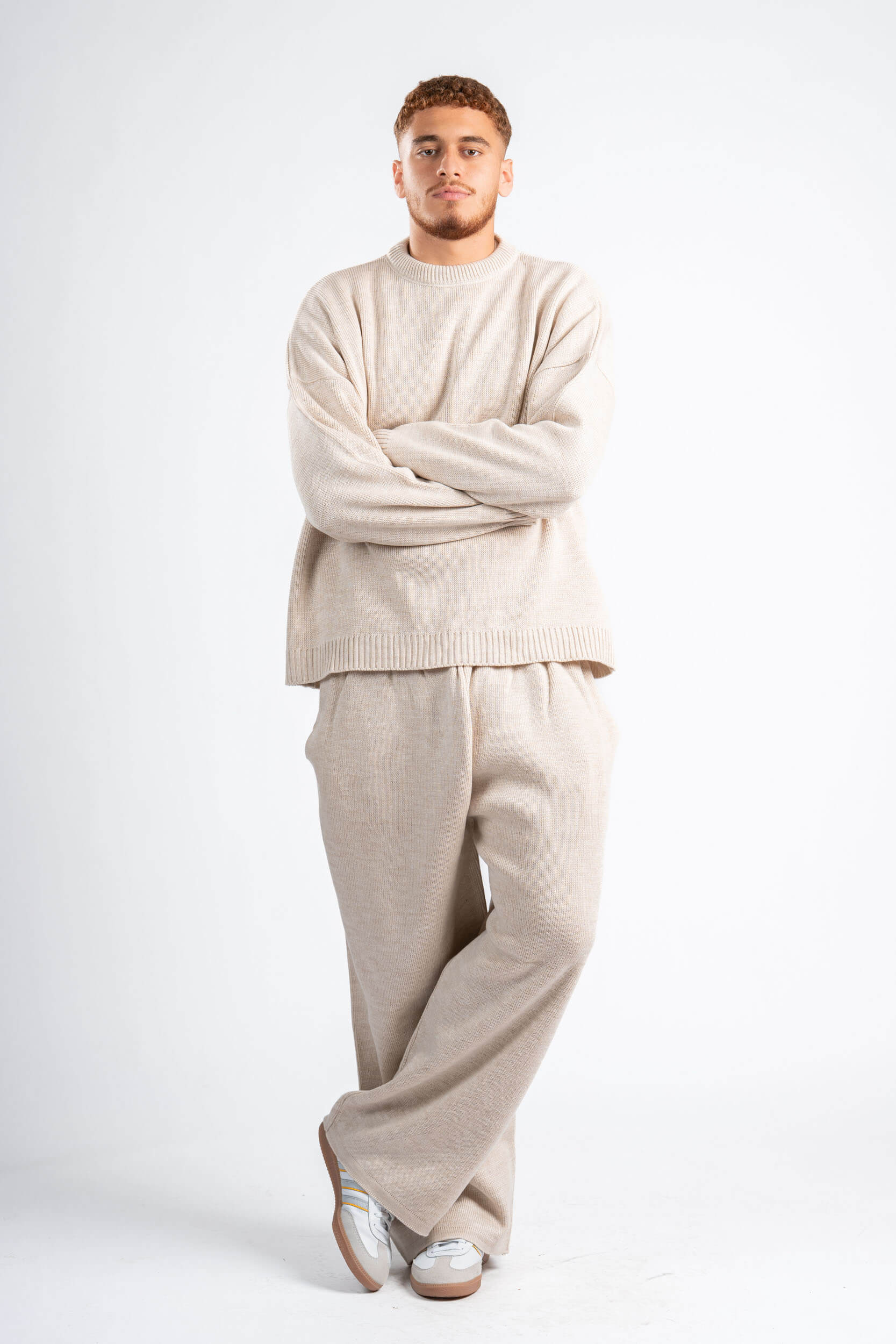 Man wearing a beige sweater and pants set on a white background