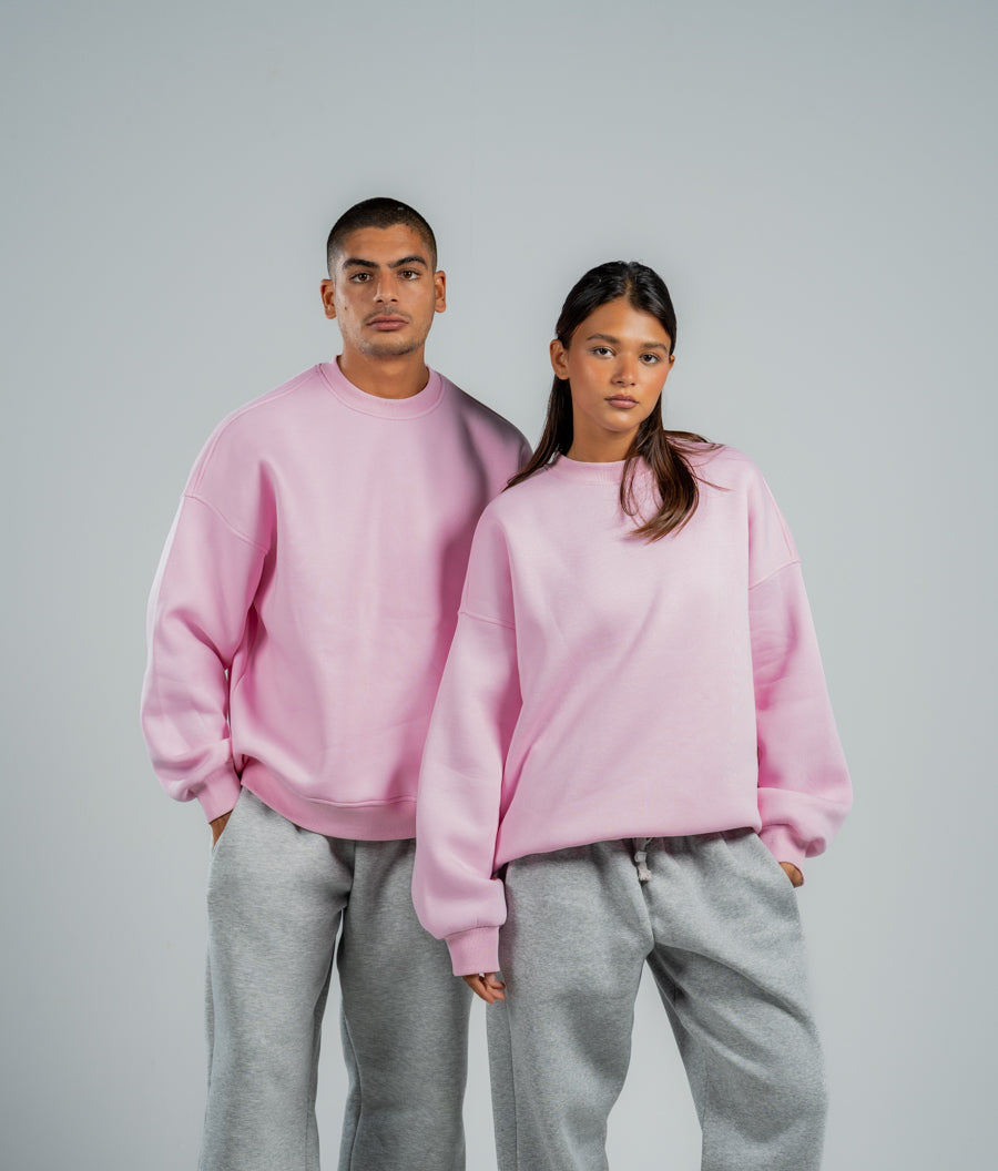 Two people wearing matching pink sweatshirts and gray pants on a plain background