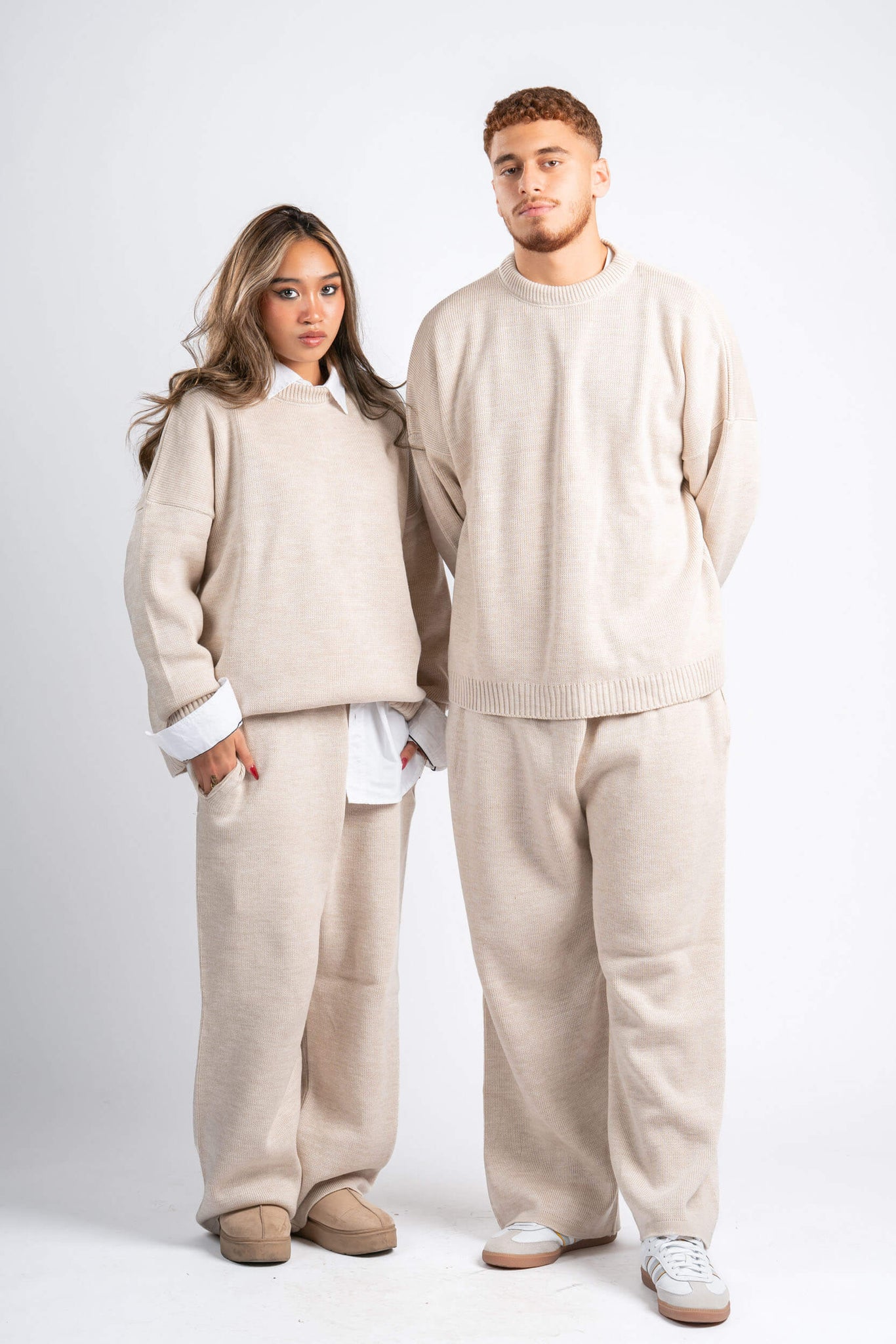 Two people wearing matching beige outfits on a white background