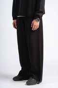 Person wearing a black outfit with wide-leg pants on a white background