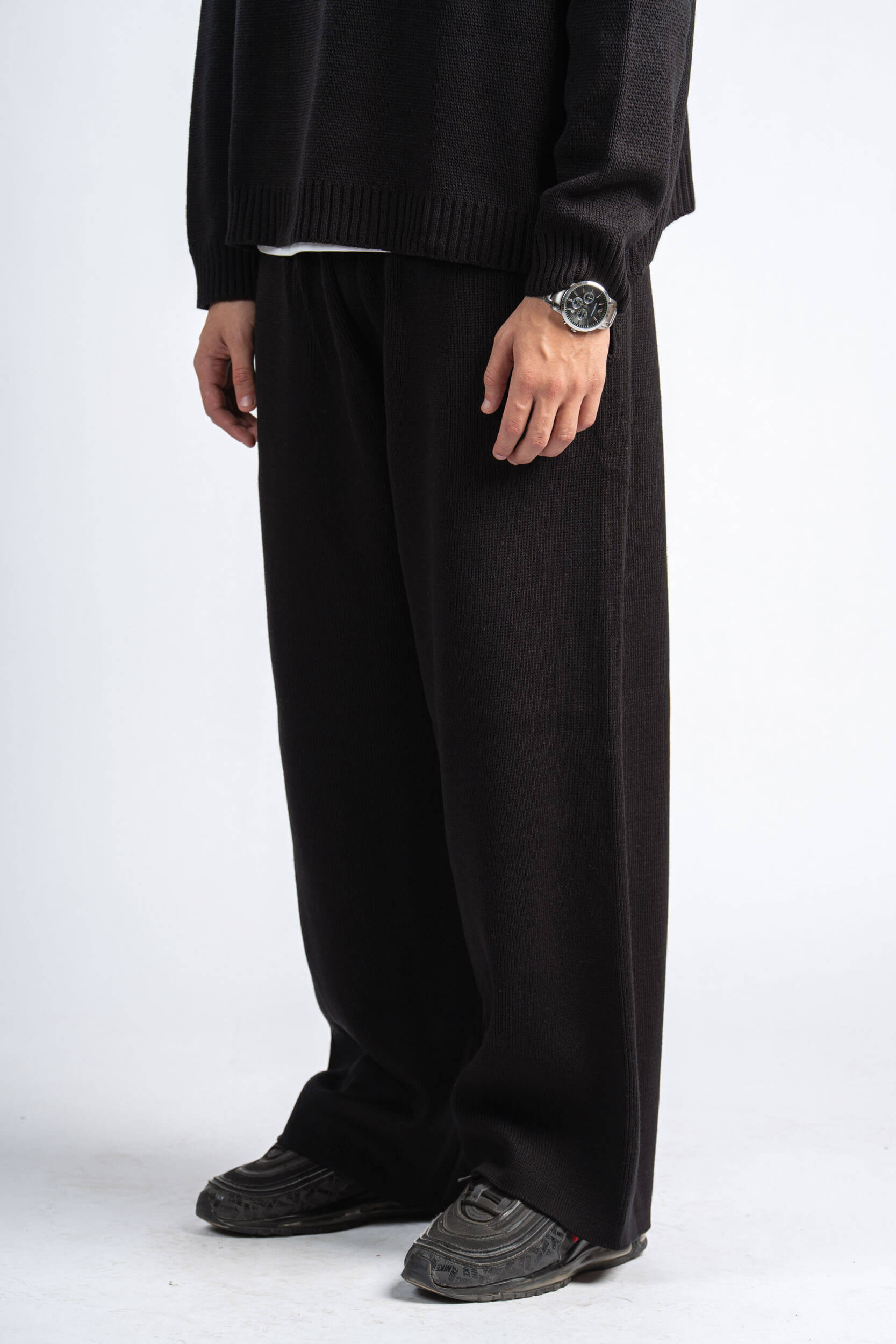 Person wearing a black outfit with wide-leg pants on a white background