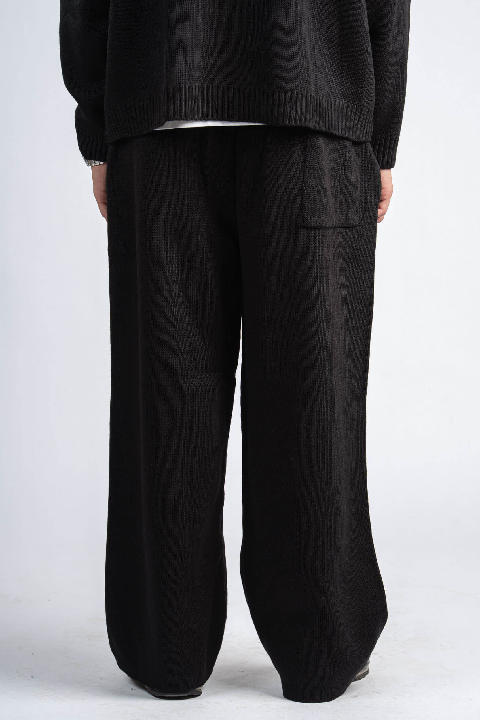 Person wearing black pants and a dark sweater on a white background