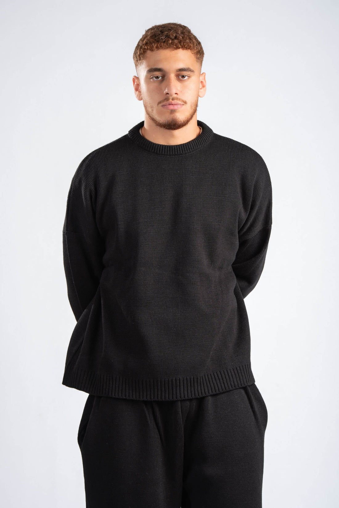 Two people wearing matching black outfits against a plain background