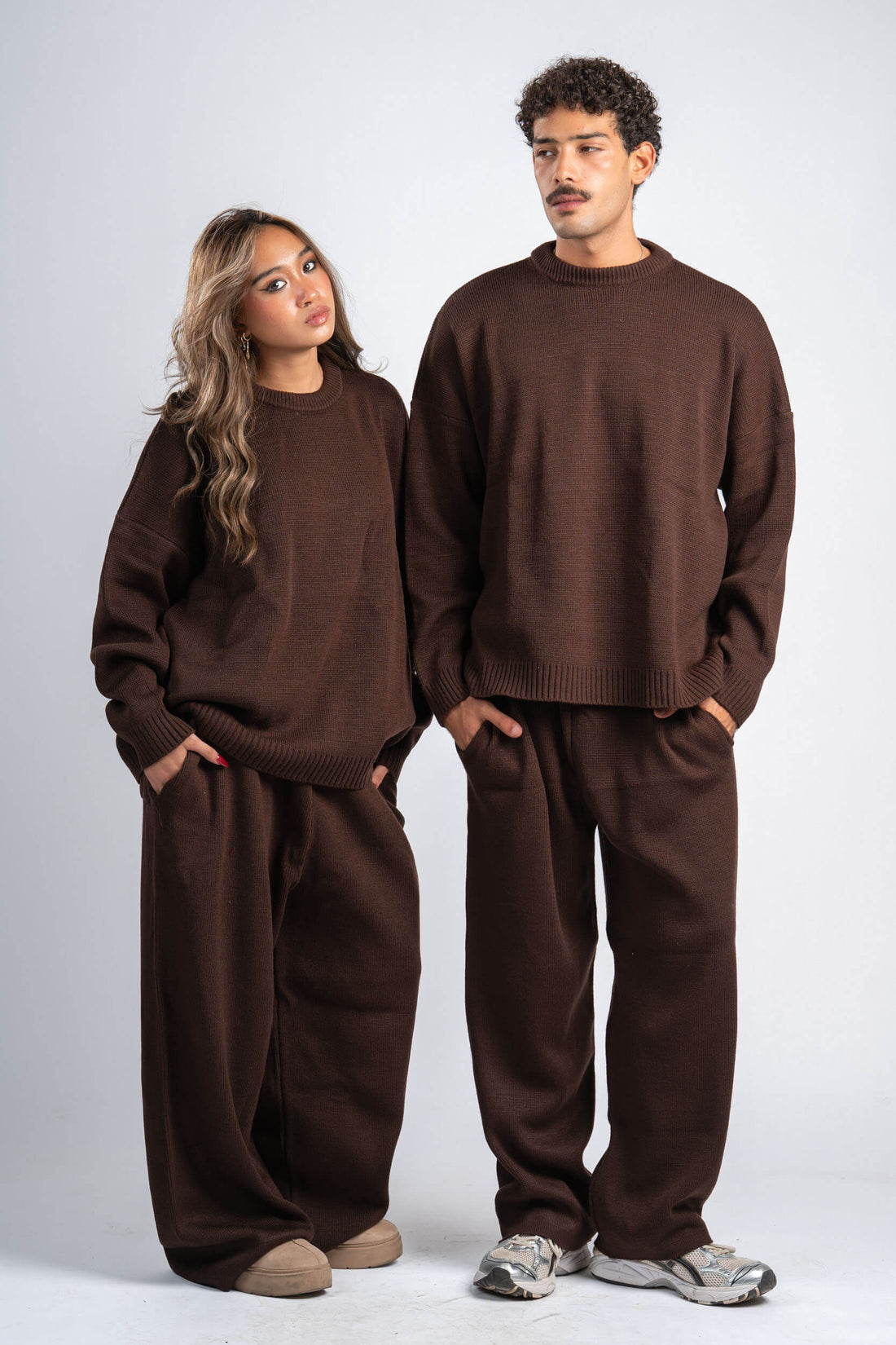 Two people wearing matching brown outfits on a white background
