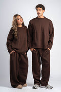 Two people wearing matching brown outfits on a white background