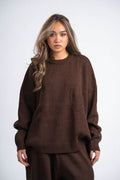 Woman wearing a brown sweater and pants on a white background