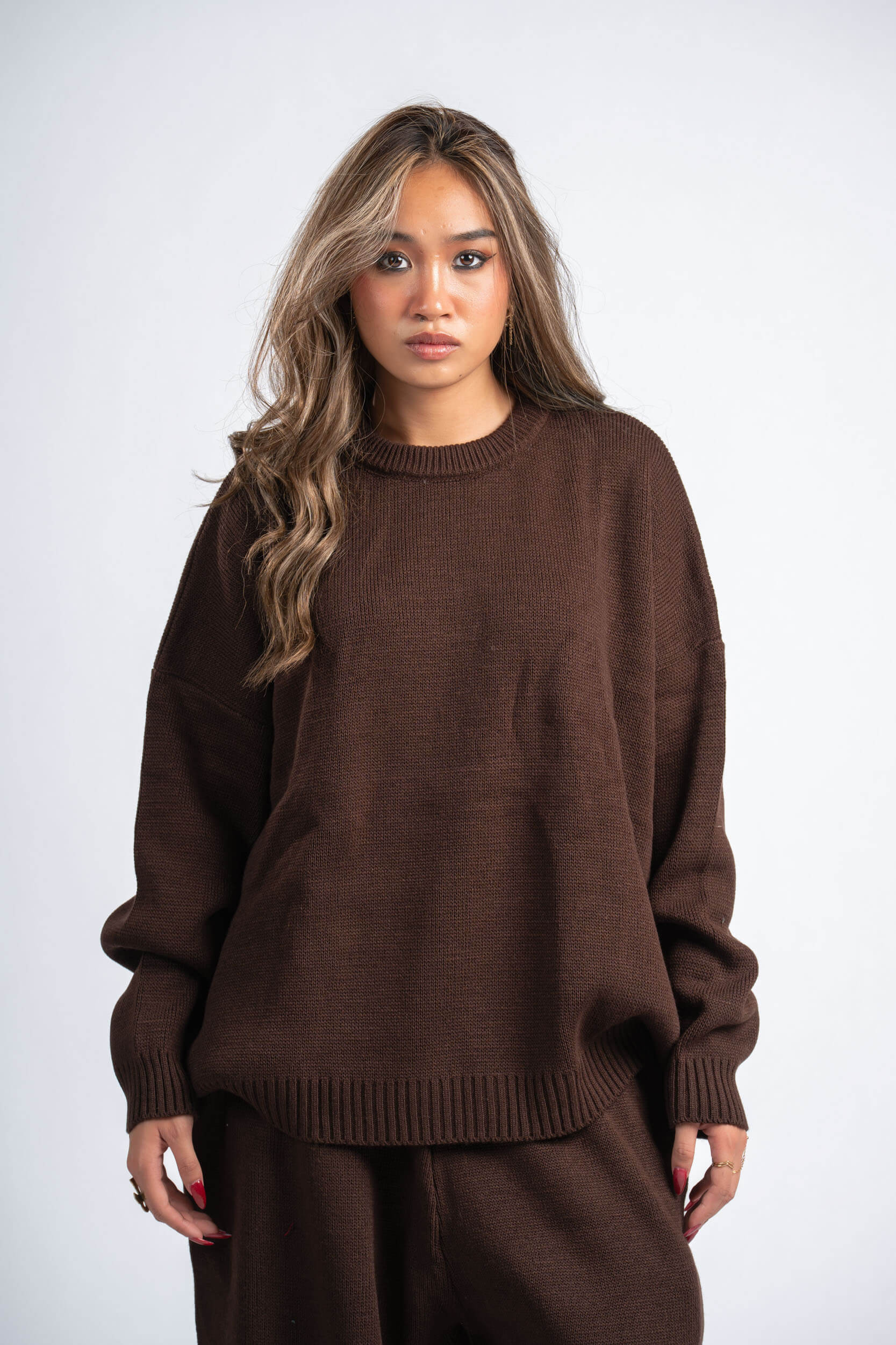 Woman wearing a brown sweater and pants on a white background