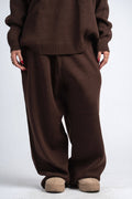 Person wearing a brown sweater and pants set on a white background