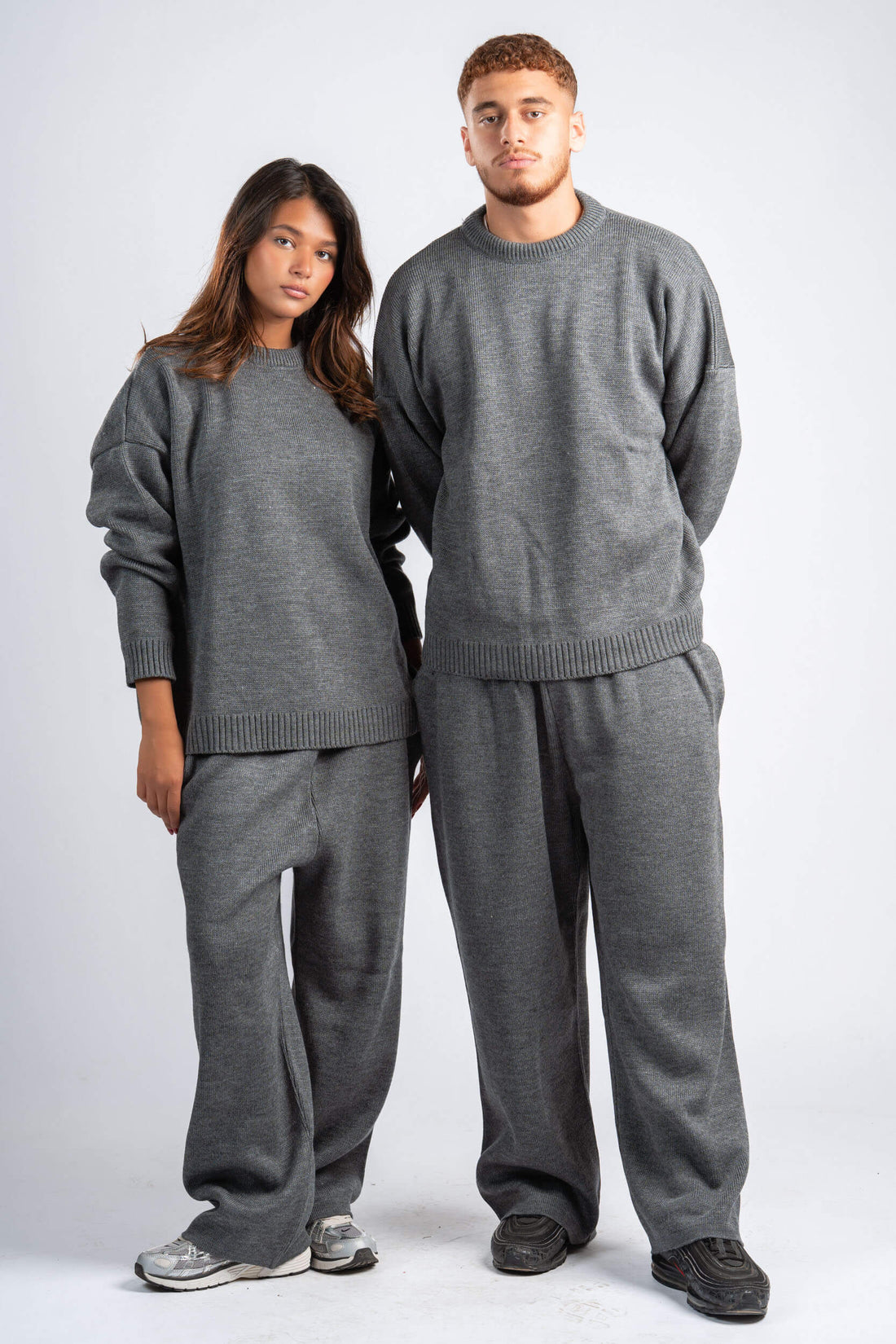 Two people wearing matching gray sweaters and pants on a white background