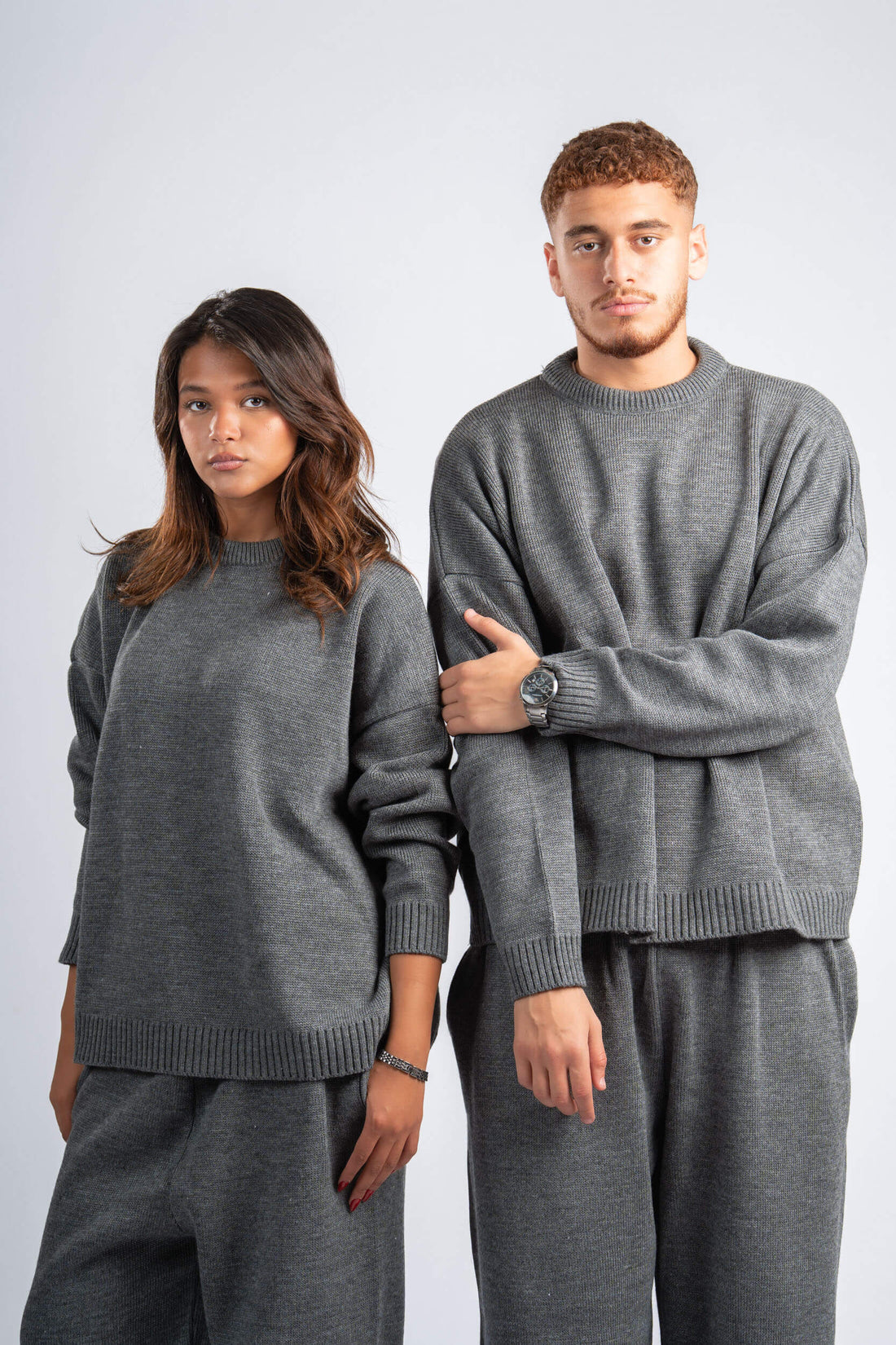 Two people wearing matching gray sweaters and pants on a white background