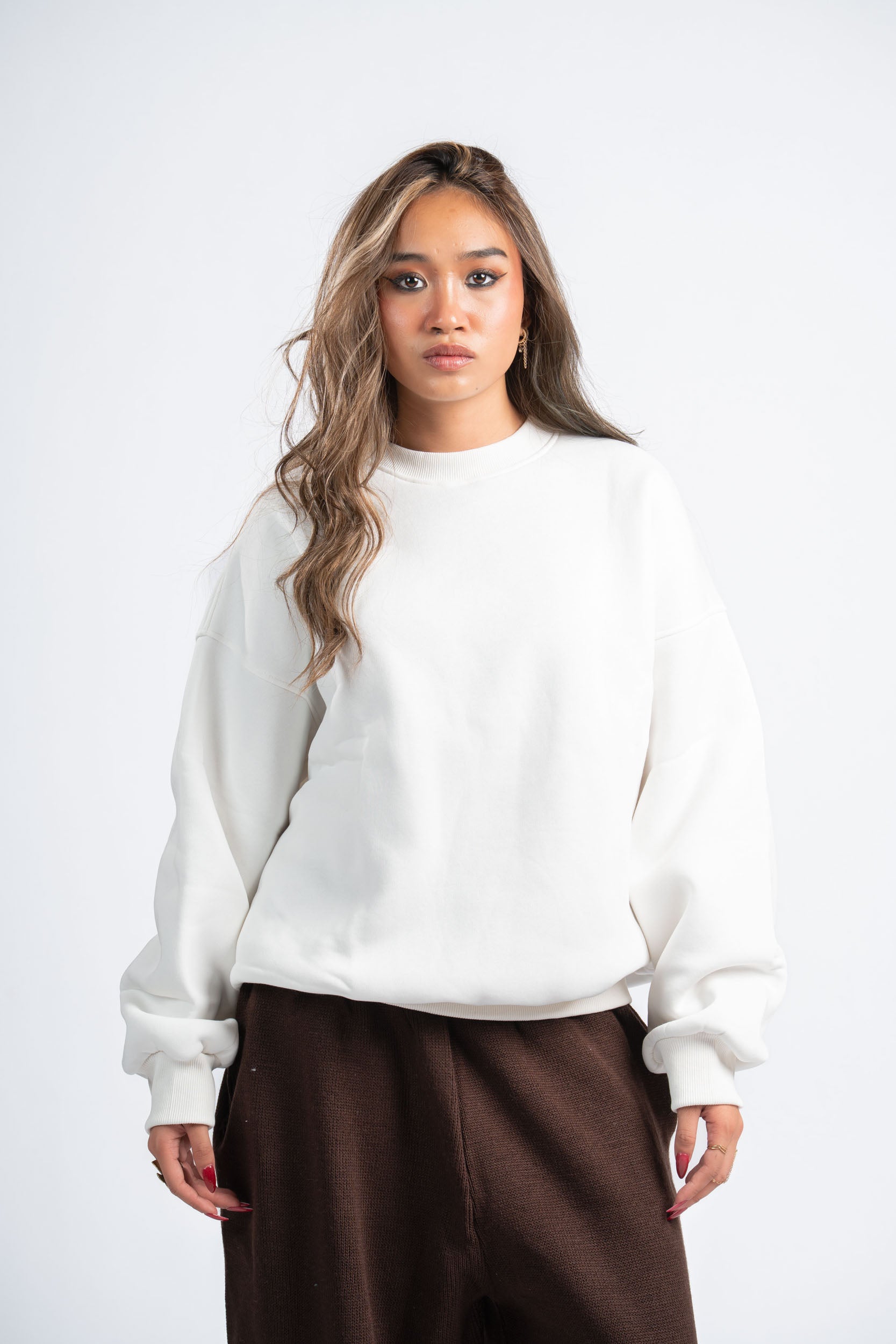 Woman wearing a white sweater and brown pants on a white background