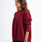 Woman wearing a maroon sweater and pants on a white background