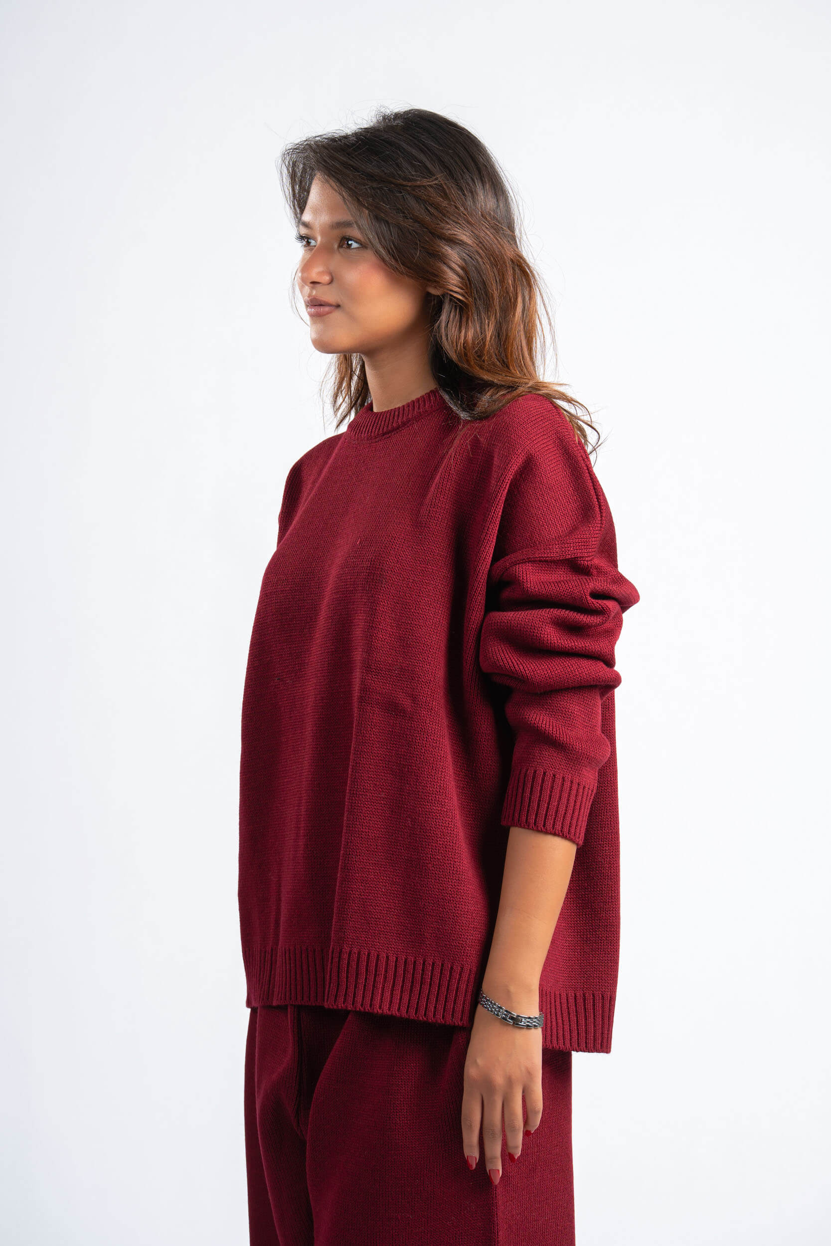 Woman wearing a maroon sweater and pants on a white background