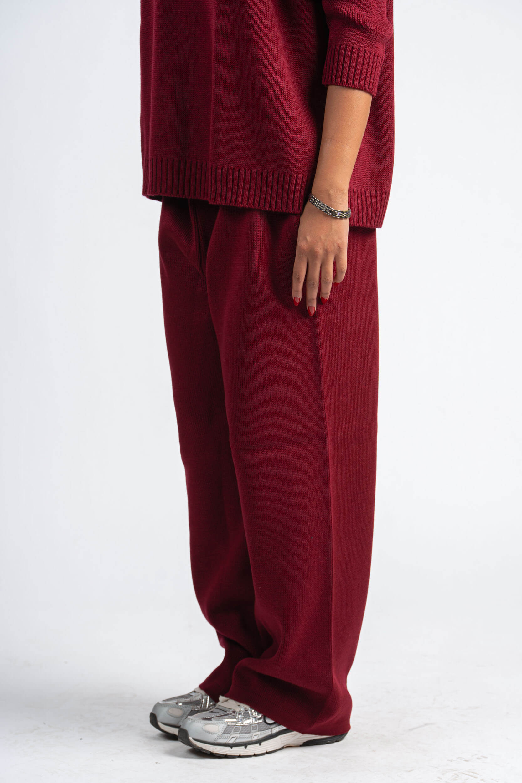 Person wearing a burgundy sweater and pants on a white background