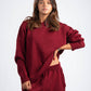 Woman wearing a maroon sweater and pants on a white background