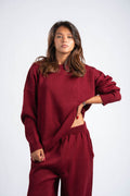 Woman wearing a maroon sweater and pants on a white background