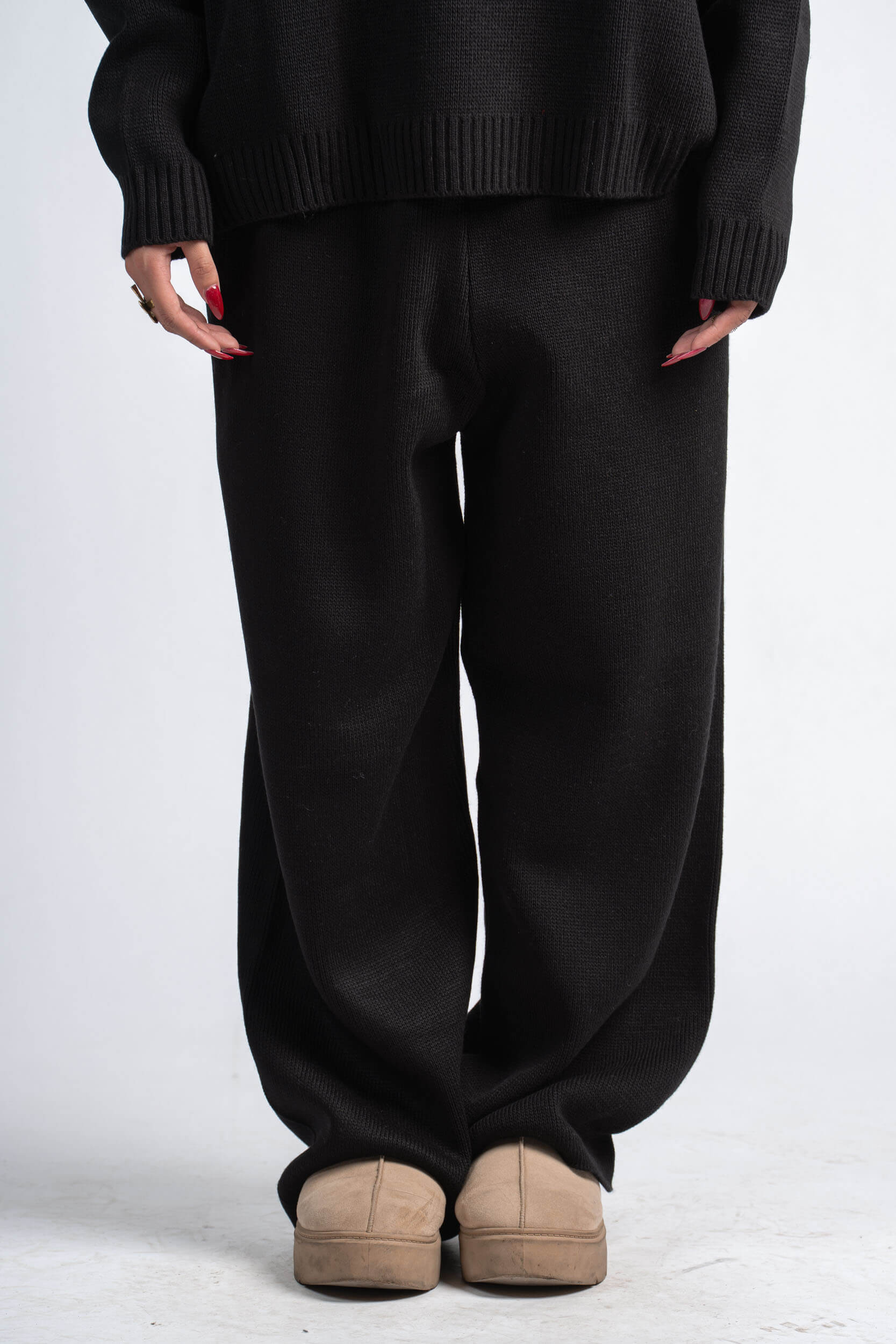 Person wearing a black sweater and black pants on a white background