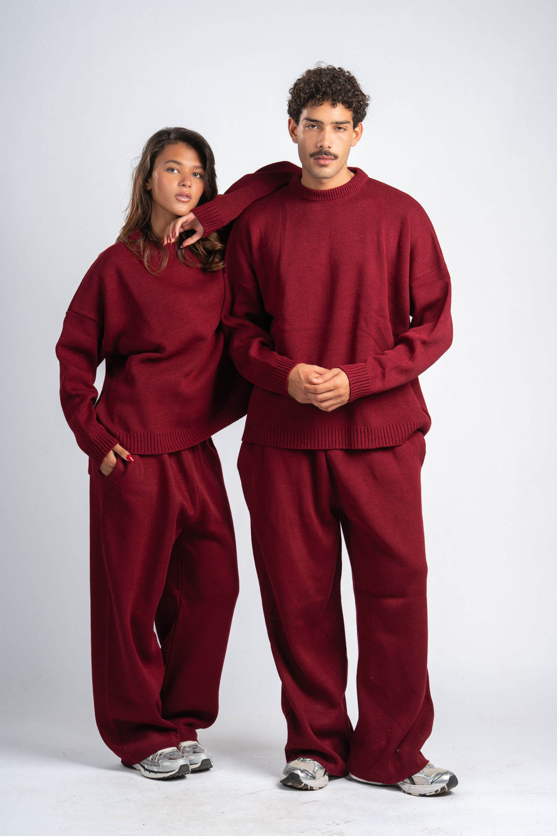 Two people wearing matching red sweatsuits on a white background