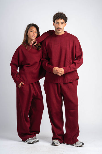 Two people wearing matching red sweatsuits on a white background