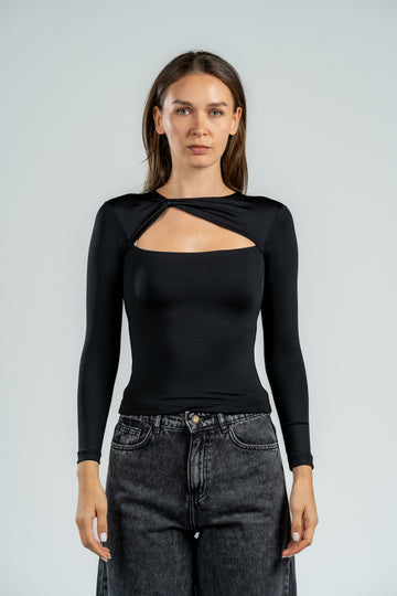 Woman wearing a black long-sleeve top with a unique design, standing against a plain background.