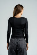 Person wearing a black long-sleeve top and gray jeans on a light gray background