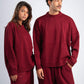Two people wearing matching red sweaters and pants on a white background