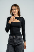 Woman wearing a black long-sleeve top with cut-out design and high-waisted dark jeans on a light gray background