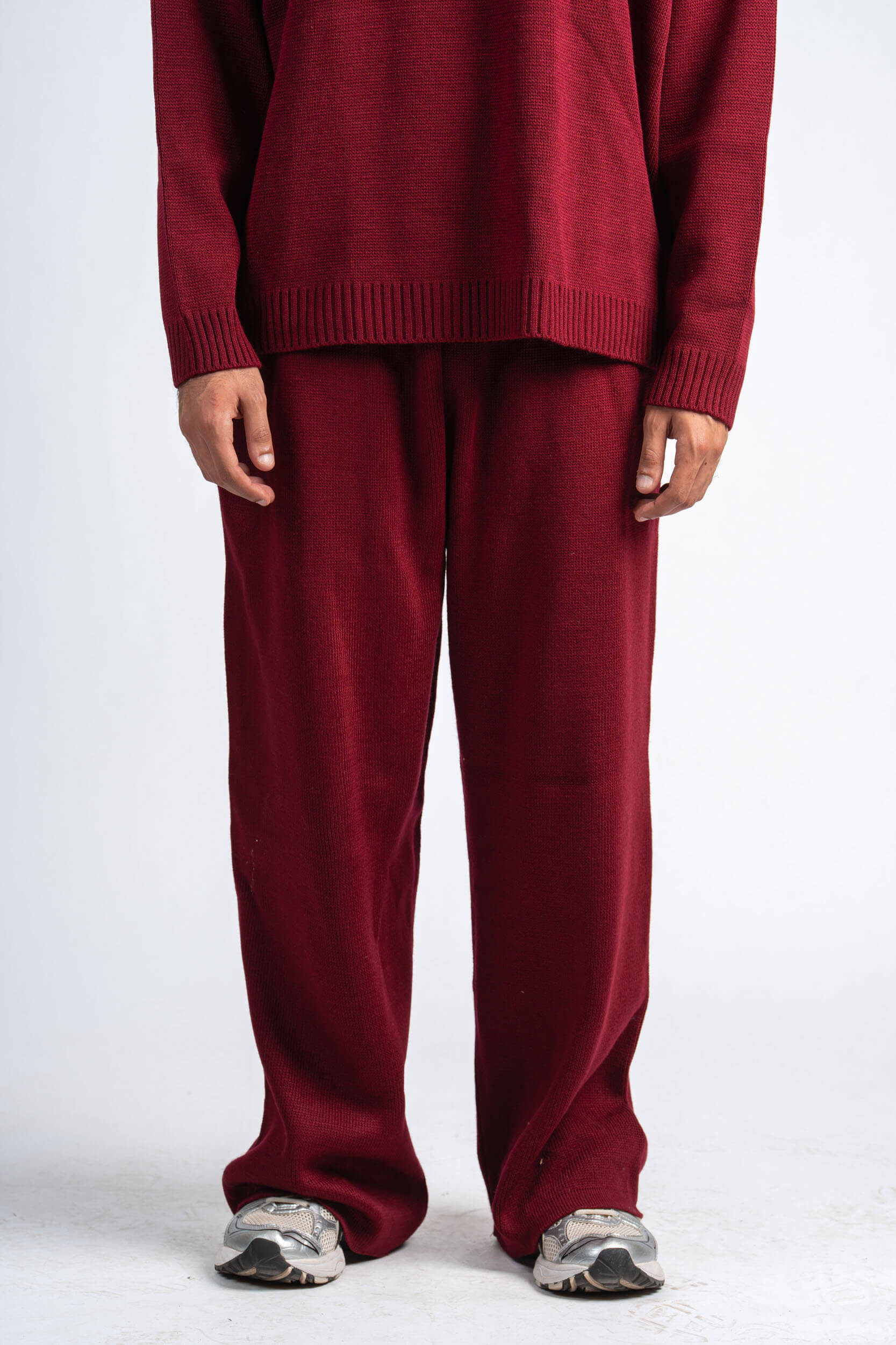 Person wearing a red sweater and matching pants on a white background