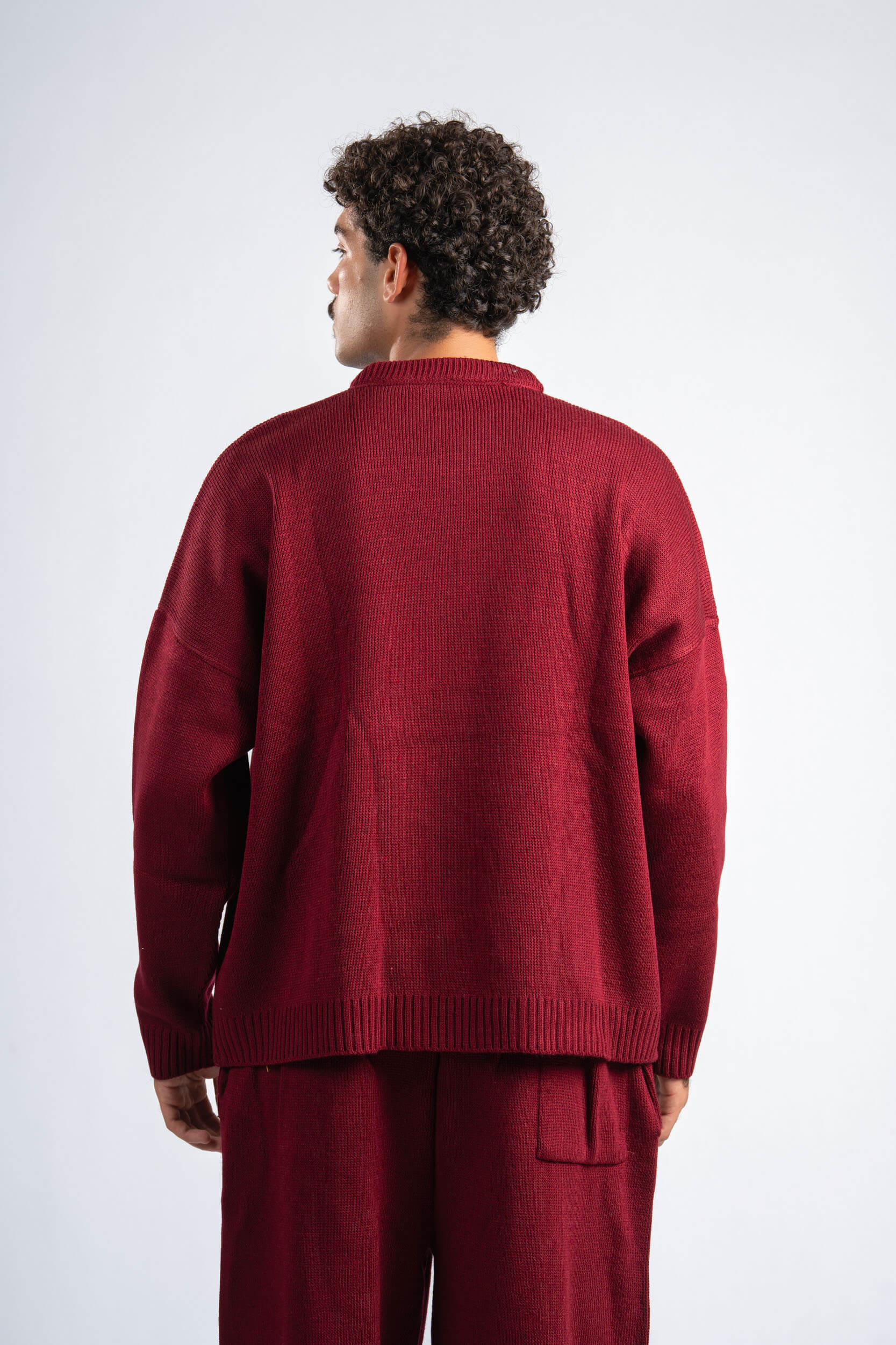 Person wearing a burgundy sweater and pants on a white background
