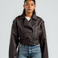 Person wearing a brown leather jacket and blue jeans against a white background