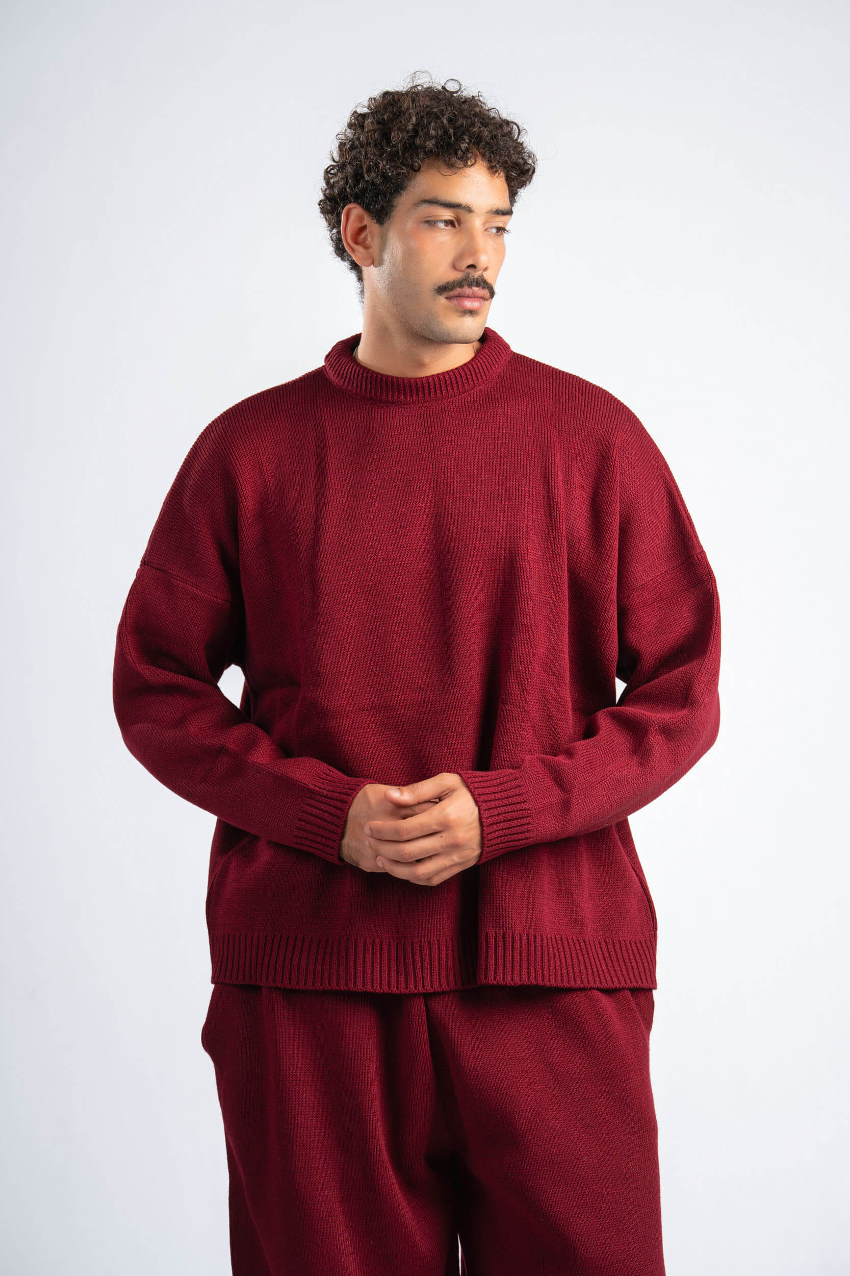 Man wearing a red sweater and pants on a white background