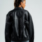 Person wearing a black leather jacket on a plain background