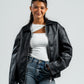 Person wearing a black leather jacket and blue jeans on a white background