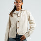 Woman wearing a beige jacket with button details on a white background