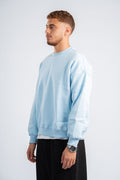 Man wearing a light blue sweatshirt and black pants on a white background