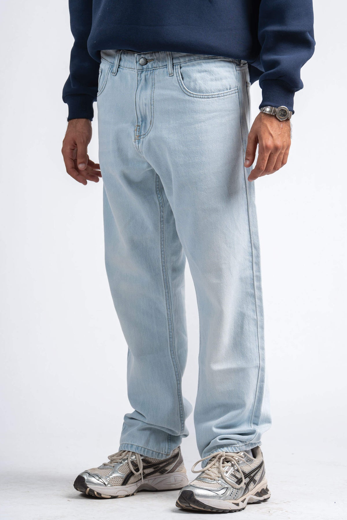 Person wearing light blue jeans and a navy sweater on a white background