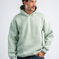 Man wearing a light green hoodie and blue jeans on a white background
