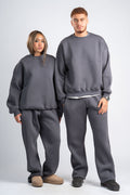 Two people wearing matching gray sweatshirt and pants sets on a plain background