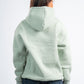 Person wearing a light green hoodie from behind on a white background