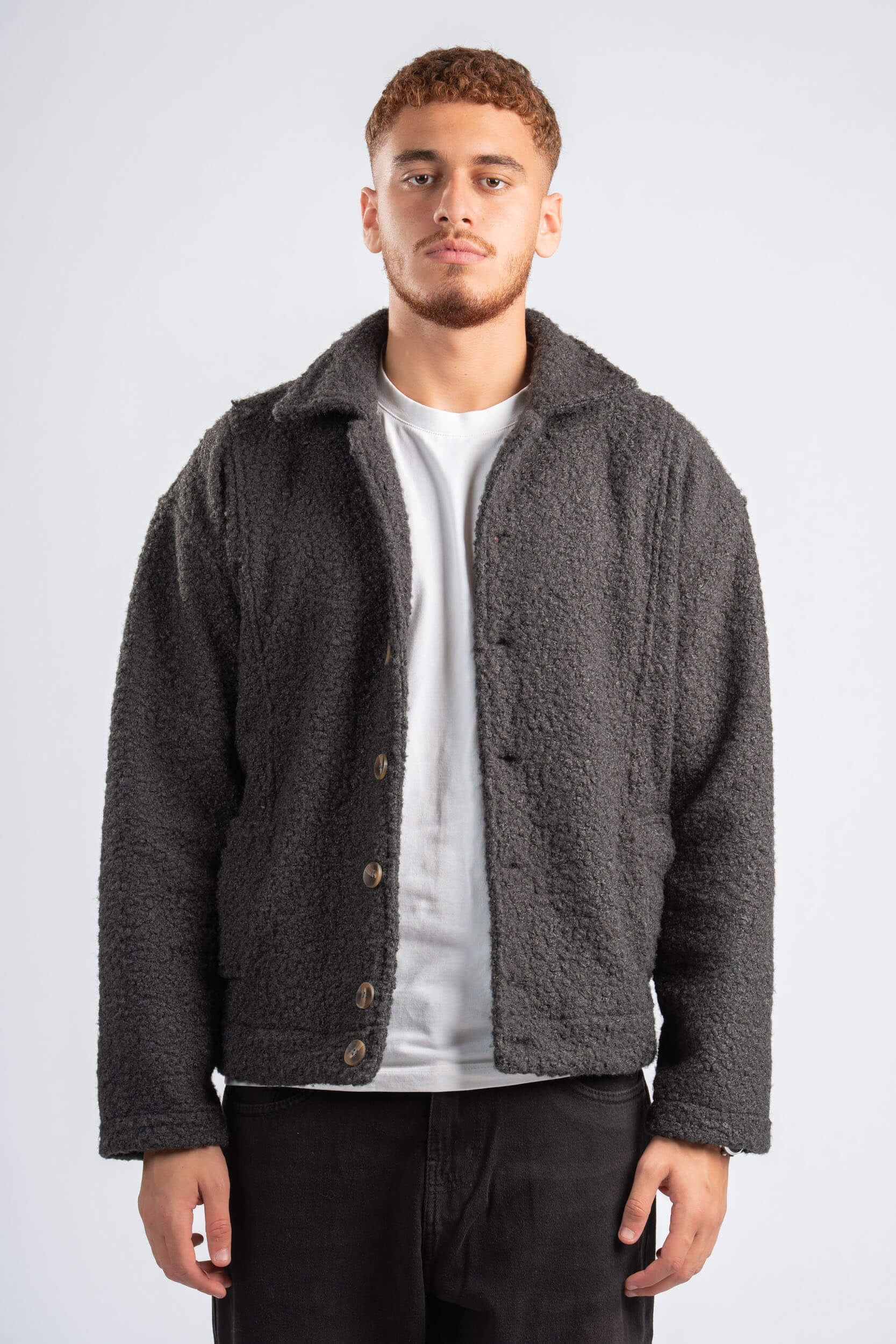 Man wearing a gray fleece jacket over a white shirt on a white background