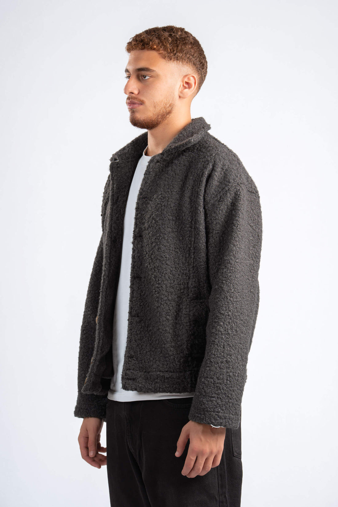 Man wearing a gray fleece jacket over a white shirt on a white background