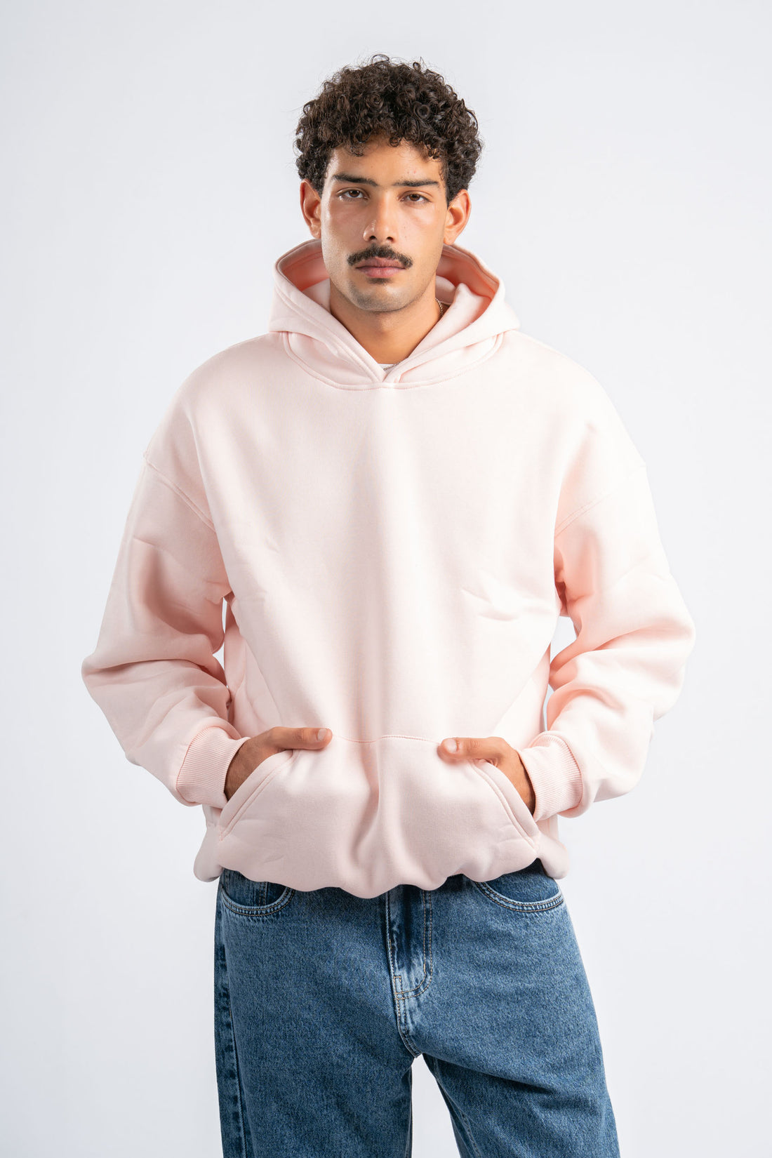 Two people wearing pink hoodies and blue jeans on a white background