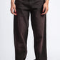 Person wearing dark brown wide-leg jeans on a white background