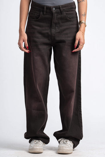 Person wearing dark brown wide-leg jeans on a white background