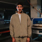 Man wearing a beige jacket and pants standing in an industrial setting