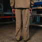 Person wearing a beige jacket and pants standing in an industrial setting