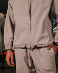 Close-up of a person wearing a beige tracksuit with a blurred background